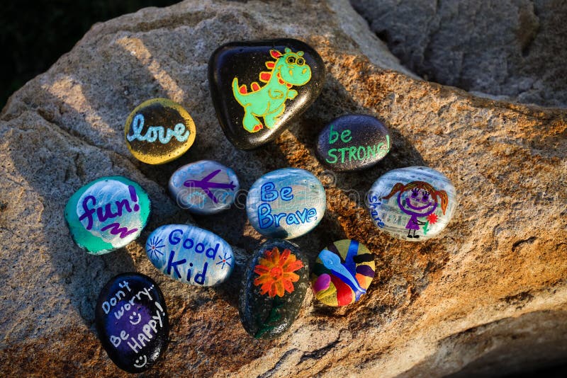Zehn gemalte Felsen auf einem Flussstein