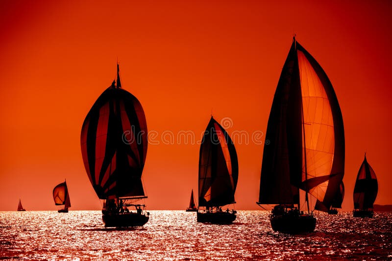 Zeilboten silhouet in volle zee op oranje zonsondergang