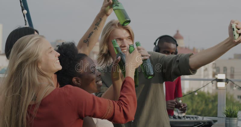 Zeitlupe aufgeregter Jugendlicher, die sich mit einer Smartphone-Kamera selbstständig machen und die Party im Freien auf dem Dach