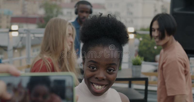 Zeitlupe der afrikanischen Amerikanerin posiert für Smartphone-Kamera mit Bierflasche und genießt die Party auf dem Dach mit Freun