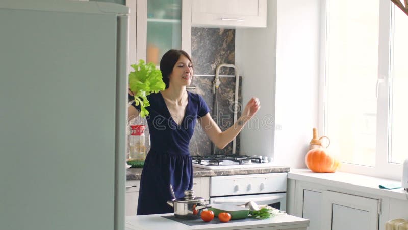 Zeitlupe des lustigen Frauenkochtanzes mit grünem Kopfsalat beim in der Küche zu Hause kochen
