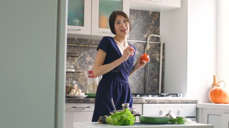 Zeitlupe des lustigen Frauenkochtanzes mit grünem Kopfsalat beim in der Küche zu Hause kochen