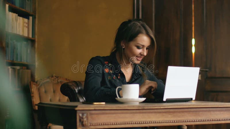 Zeitlupe des lächelnden Studentenmädchens, das zuhause an Laptop in der Universitätsbibliothek arbeitet