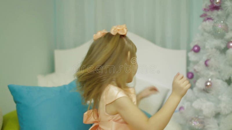 Zeitlupeansicht des glücklichen kleinen Mädchens in werfendem Kissen des Schlafzimmers an der Kamera