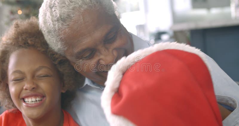 Zeitlupereihenfolge des Jungen und des Mädchens, die auf Sofa mit Großvater zur Weihnachtszeit sitzen