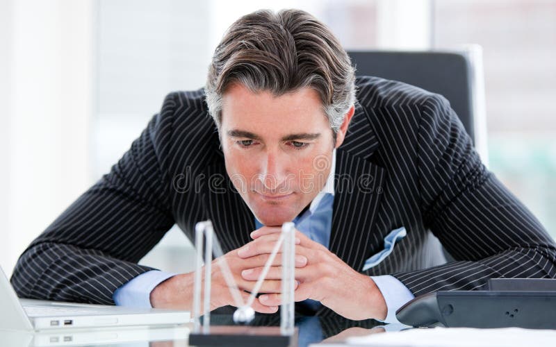 Zekere zakenman die kinetische ballen bekijkt stock afbeeldingen Zekere zakenman die kinetische ballen bekijkt stock afbeeldingen