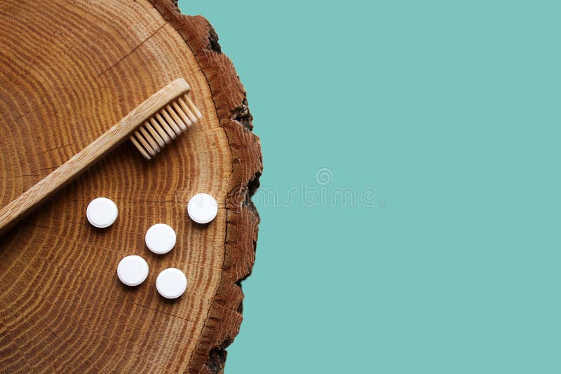 Zero waste flat lay. Bamboo toothbrush, toothpaste tablets on wooden background.