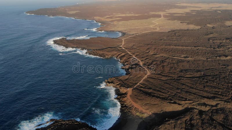 Zicht vanuit de lucht op de kustlijn met lava en oceaan met zonnige tonen