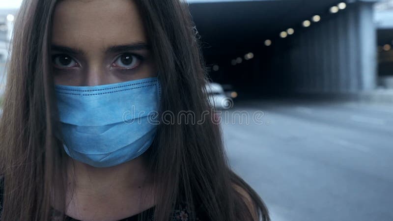 Ziek jong vrouwelijk het zetten veiligheidsmasker, grote stadsverontreiniging, epidemisch virus
