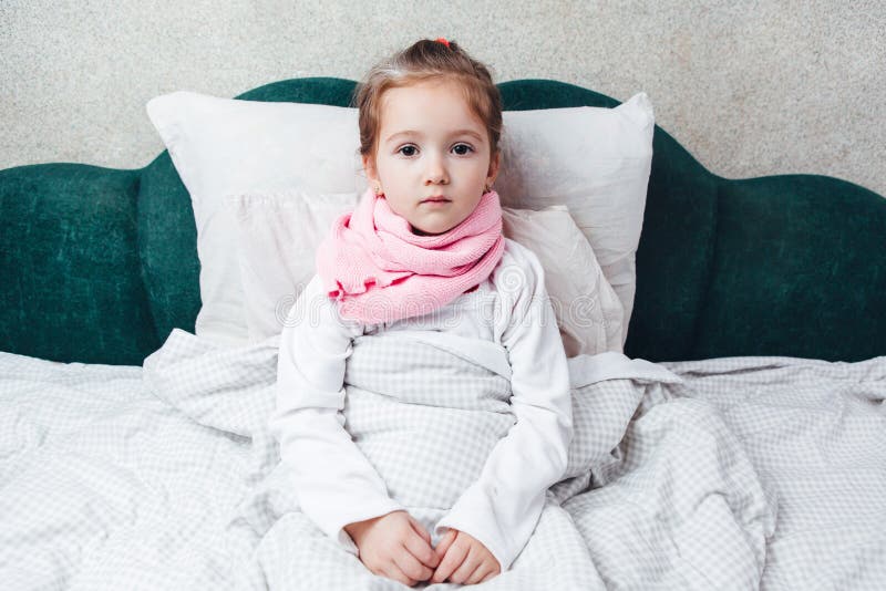 Ziek meisje die in het bed in roze sjaal liggen stock foto Ziek meisje die in het bed in roze sjaal liggen stock foto