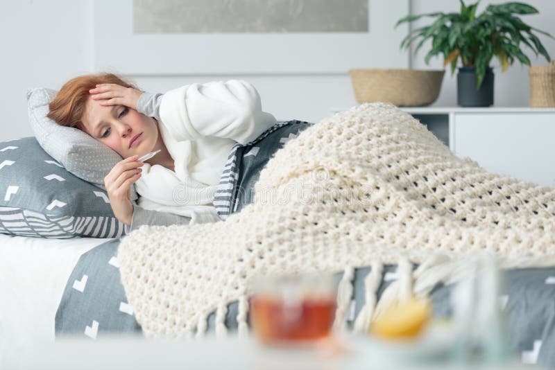 Zieke vrouw die thermometer bekijken royalty-vrije stock afbeelding Zieke vrouw die thermometer bekijken royalty-vrije stock afbeelding