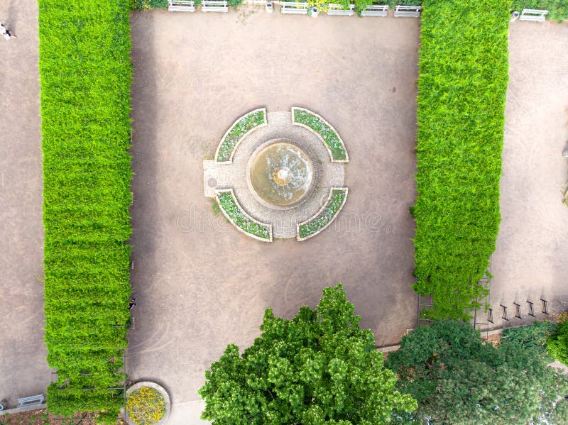 A view from a drone over green pergolas overgrown with ivy and a small fountain. A view from a drone over green pergolas overgrown with ivy and a small fountain