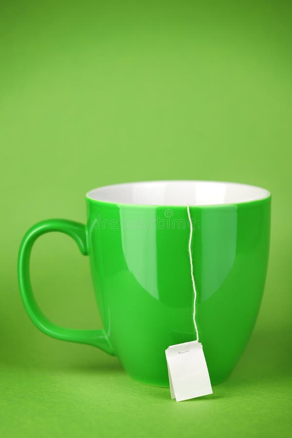 Green Tea cup on green background, label of a teabag hanging down, very shallow DoF. Green Tea cup on green background, label of a teabag hanging down, very shallow DoF