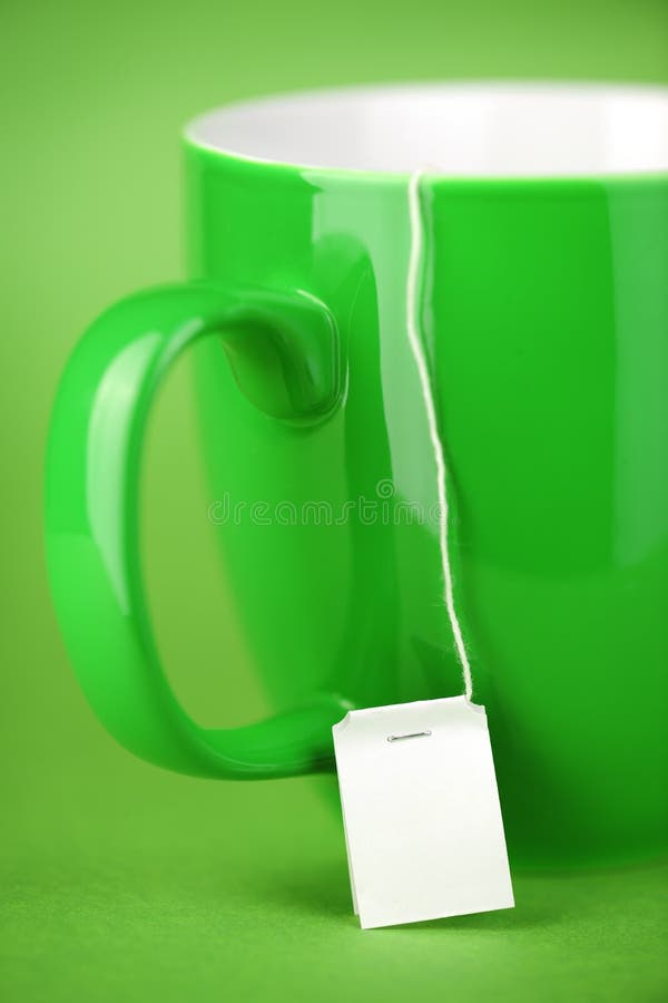 Green Tea cup on green background, label of a teabag hanging down, very shallow DoF. Green Tea cup on green background, label of a teabag hanging down, very shallow DoF