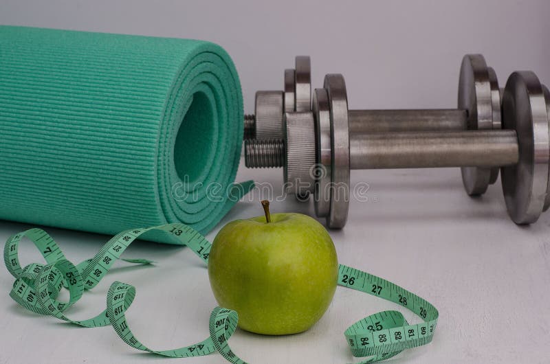 Zielony jabłko z dumbbells, dywanikiem i taśmą, ?e?ska sprawno?? fizyczna obrazy stock Zielony jabłko z dumbbells, dywanikiem i taśmą, ?e?ska sprawno?? fizyczna obrazy stock