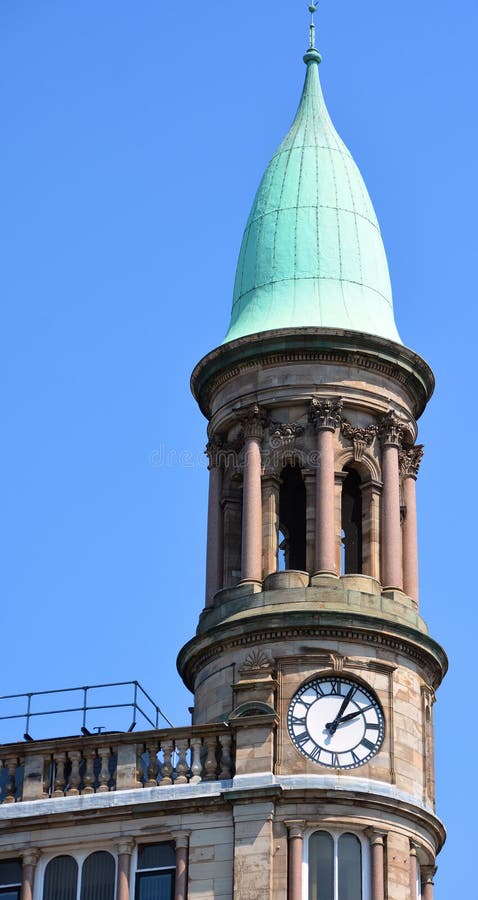 BELFAST NORTHERN IRELAND UNITED KINGDOM 06 03 2023: Green copper ogee dome and tower clock on old Robinson and Cleavers department store in belfast designed by Young and Mackenzie. BELFAST NORTHERN IRELAND UNITED KINGDOM 06 03 2023: Green copper ogee dome and tower clock on old Robinson and Cleavers department store in belfast designed by Young and Mackenzie