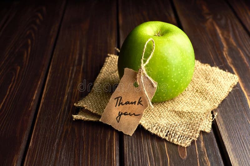 Zielony prezent jabłkowy z podziękowaniami na ciemnym drewnianym stole. dzień nauczyciela