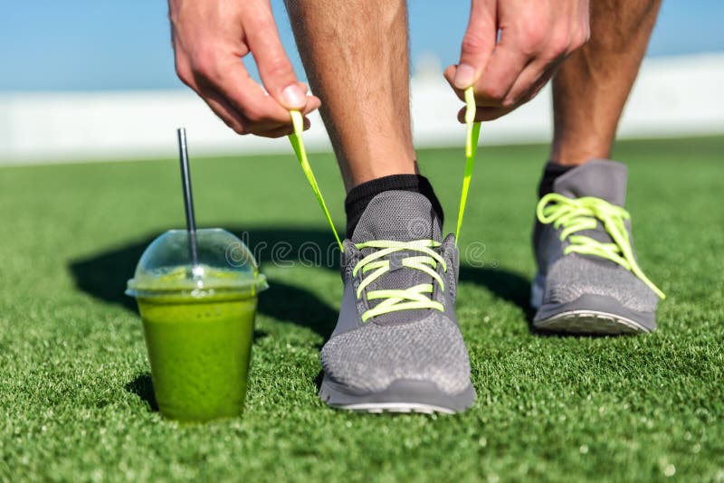 Zielony smoothie sprawności fizycznej mężczyzna wiąże działających buty