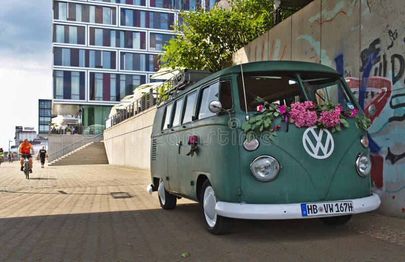 Zielony VW T3 samochód dostawczy z wielkim bielu VW logem z nowożytną szklaną fasadą w tle Bremen Niemcy, Lipiec - 17th, 2018 - zdjęcia royalty free Zielony VW T3 samochód dostawczy z wielkim bielu VW logem z nowożytną szklaną fasadą w tle Bremen Niemcy, Lipiec - 17th, 2018 - zdjęcia royalty free