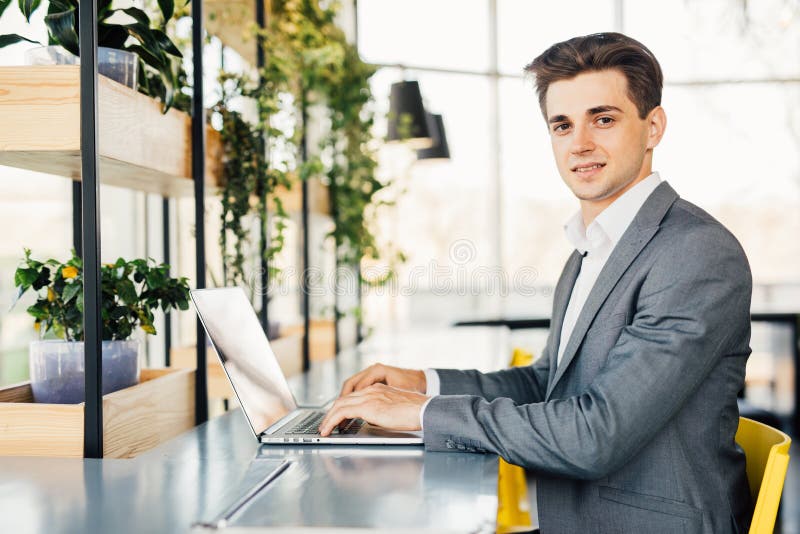 Zijaanzicht van bedrijfsmensenzitting door de lijst met laptop computer en het bekijken camera royalty-vrije stock foto's Zijaanzicht van bedrijfsmensenzitting door de lijst met laptop computer en het bekijken camera royalty-vrije stock foto's