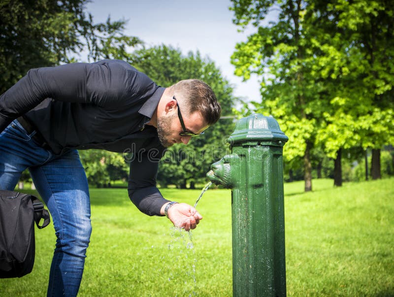 Zijaanzicht van gebaard zakenman drinkwater van parkfontein stock afbeeldingen Zijaanzicht van gebaard zakenman drinkwater van parkfontein stock afbeeldingen