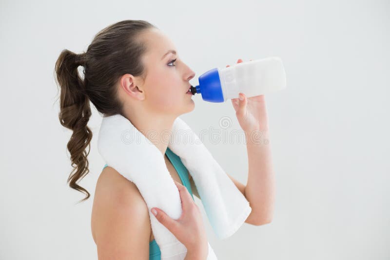 Zijaanzicht van geschikt vrouwen drinkwater bij de gymnastiek stock foto Zijaanzicht van geschikt vrouwen drinkwater bij de gymnastiek stock foto