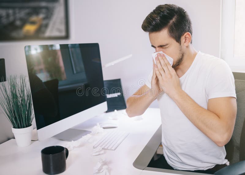 Zijaanzicht van patient& x27; s werkgever het niezen in een weefsel in een bureau dichtbij het venster in de computer freelancer stock fotografie Zijaanzicht van patient& x27; s werkgever het niezen in een weefsel in een bureau dichtbij het venster in de computer freelancer stock fotografie