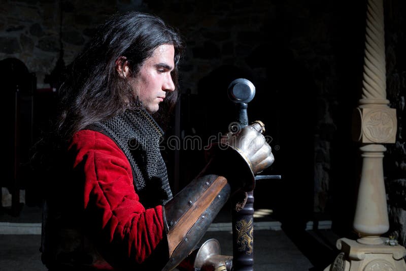 Zijaanzicht van Ridder With Sword Looking neer tegen Zwarte Achtergrond royalty-vrije stock foto's Zijaanzicht van Ridder With Sword Looking neer tegen Zwarte Achtergrond royalty-vrije stock foto's