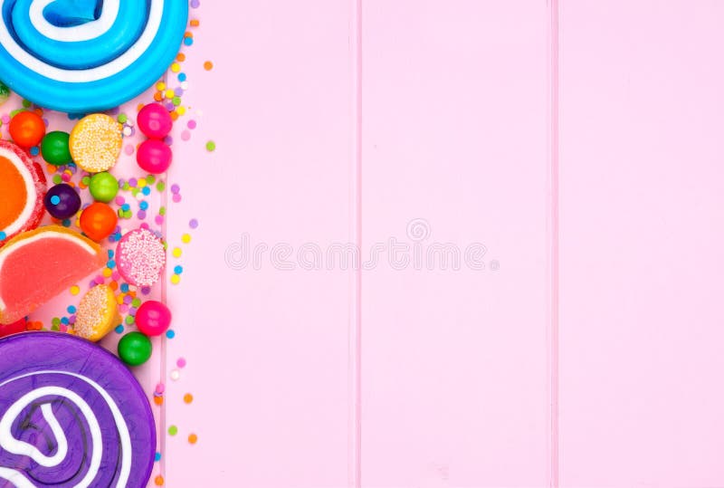 Zijgrens van geassorteerd kleurrijk suikergoed tegen roze hout