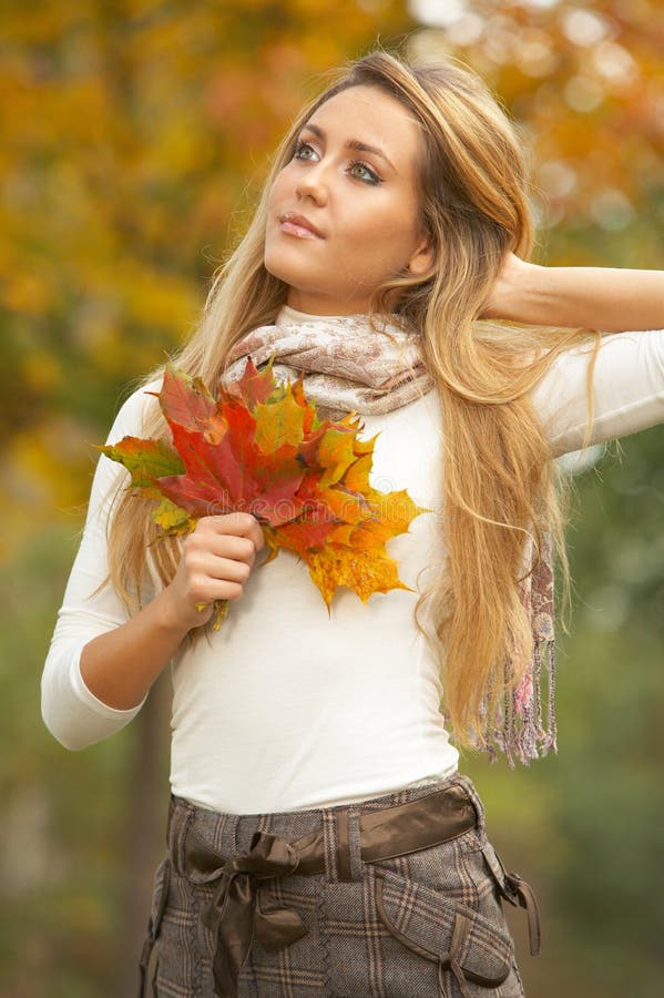 20-25 years old beautiful woman portrait holding leafs in natural autumn outdoors. 20-25 years old beautiful woman portrait holding leafs in natural autumn outdoors