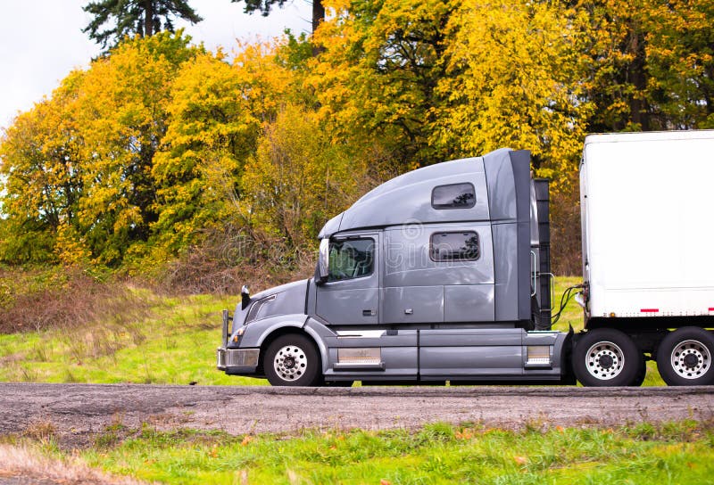 Zilveren grote installatie semi vrachtwagen met droge bestelwagen semi aanhangwagen die op aut gaan stock foto Zilveren grote installatie semi vrachtwagen met droge bestelwagen semi aanhangwagen die op aut gaan stock foto