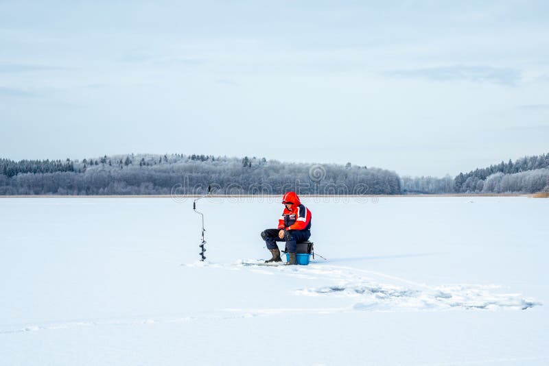 JARFALLA, SWEDEN - JANUARY 27, 2019: Winter landscape view of one elderly male on a frozen lake ice fishing in Jarfalla Sweden January 27, 2019. JARFALLA, SWEDEN - JANUARY 27, 2019: Winter landscape view of one elderly male on a frozen lake ice fishing in Jarfalla Sweden January 27, 2019