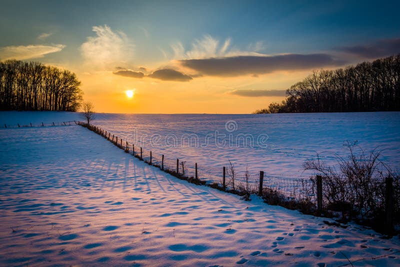 Zima zmierzch nad śniegiem i ogrodzeniem zakrywał rolnego pole w wiejskim obrazy stock Zima zmierzch nad śniegiem i ogrodzeniem zakrywał rolnego pole w wiejskim obrazy stock