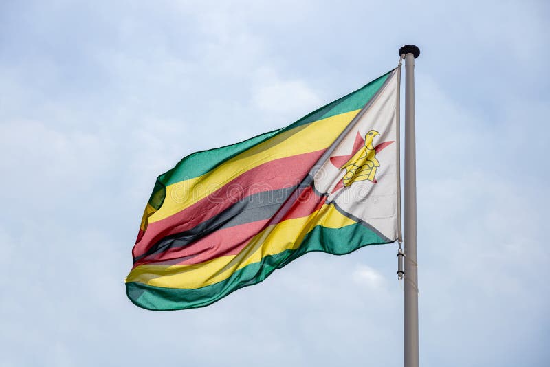Zimbabwe flagi falowanie przeciw jasnemu niebieskiemu niebu zdjęcie royalty free