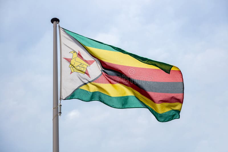 Zimbabwe flagi falowanie przeciw jasnemu niebieskiemu niebu obraz royalty free