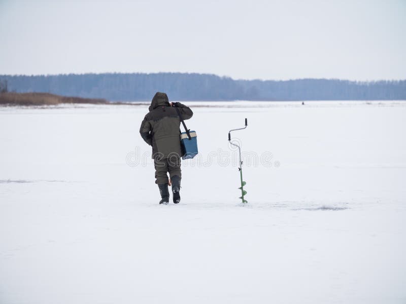 Winter ice fishing, lake, frosty day. fisherman collects gear in the snow. Winter ice fishing, lake, frosty day. fisherman collects gear in the snow