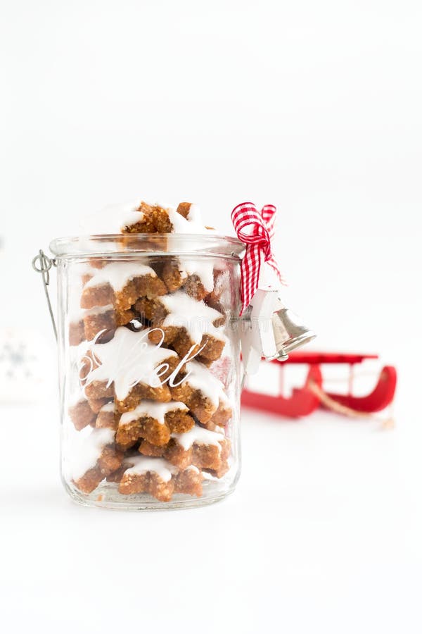 Zimtsterne, biscuits allemands de Noël dans le pot en verre de Decoated. Zimtsterne, biscuits allemands de Noël dans un pot en verre avec la décoration de Noël et un traîneau rouge à l'arrière-plan Profondeur de zone Vue d'angle faible