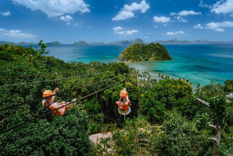 Zipline over Las Cabanas Beach with tourist on sunny day with white clouds over sea. El Nido, Palawan, Philippines