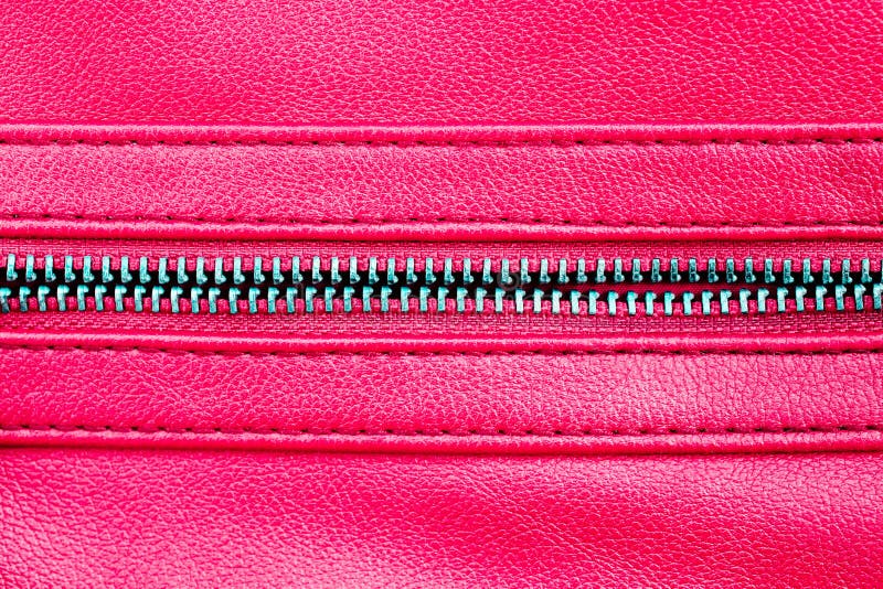Zipper open between two layers of pink fabric textile and pink leather with visible seam under high magnification close detail stock photo