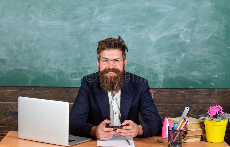 Zit leraars gebaarde hipster met oogglazen op de achtergrond van het klaslokaalbord De leraar zit bij bureau met laptop Terug naa stock afbeeldingen Zit leraars gebaarde hipster met oogglazen op de achtergrond van het klaslokaalbord De leraar zit bij bureau met laptop Terug naa stock afbeeldingen