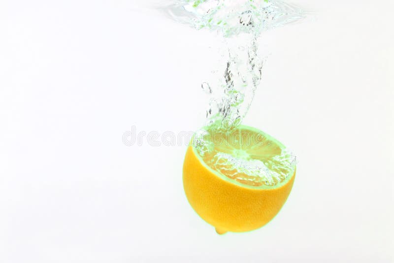 Zitrone, die in Wasser auf weißem Hintergrund fällt stockfotografie