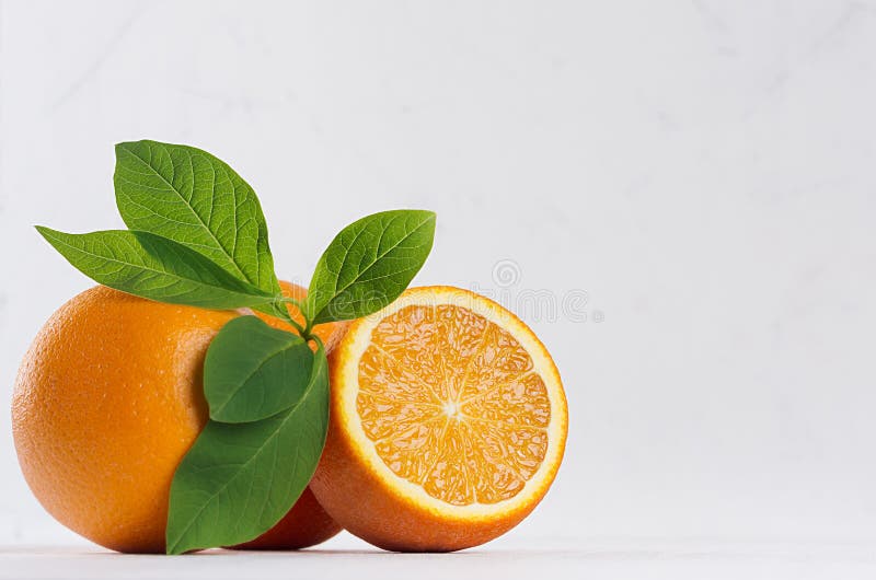 Zitrusfrucht mit halben saftigen Orangen und Grün lässt Nahaufnahme auf weißer hölzerner Tabelle lizenzfreies stockbild