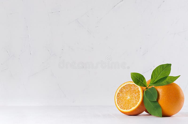 Zitrusfrucht mit halben saftigen Orangen und Grün verlässt auf weißer hölzerner Tabelle lizenzfreies stockbild