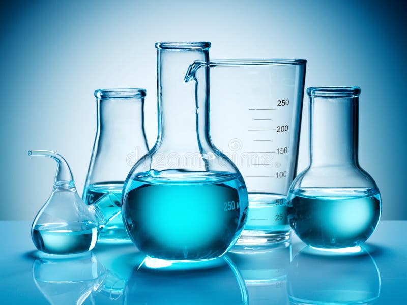 An assortment of beakers and flasks containing liquids shot in blue light. An assortment of beakers and flasks containing liquids shot in blue light.