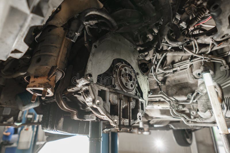 Zmiany i naprawy sprzęgło, prowadnikowy axle pracować pod podnoszącym samochodem Fachowy mechanik pracy utrzymania samochód zdjęcie stock Zmiany i naprawy sprzęgło, prowadnikowy axle pracować pod podnoszącym samochodem Fachowy mechanik pracy utrzymania samochód zdjęcie stock