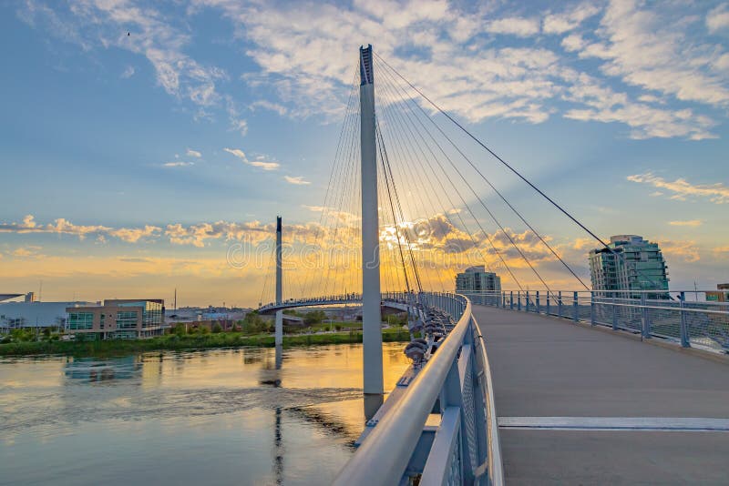 Sunset over Bob Kerrey pedestrian bridge over swollen Missouri River at Omaha Nebraska Riverfront with flooding of the Tom Hanafan River`s edge park Council Bluffs Iowa. Flood of 2019. Sunset over Bob Kerrey pedestrian bridge over swollen Missouri River at Omaha Nebraska Riverfront with flooding of the Tom Hanafan River`s edge park Council Bluffs Iowa. Flood of 2019.