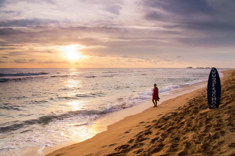 Zmierzch w Hikkaduwa plaży z damą w czerwieni, zdjęcia stock Zmierzch w Hikkaduwa plaży z damą w czerwieni, zdjęcia stock