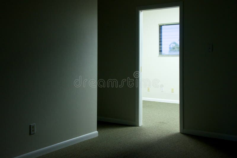 Looking towards an empty well lit office with open door, most of image is in shadow. Looking towards an empty well lit office with open door, most of image is in shadow