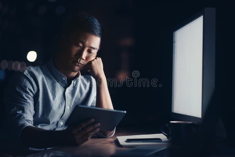 Zmęczony Azjatycki biznesmen pracuje online w ciemnym biurze obraz royalty free Zmęczony Azjatycki biznesmen pracuje online w ciemnym biurze obraz royalty free