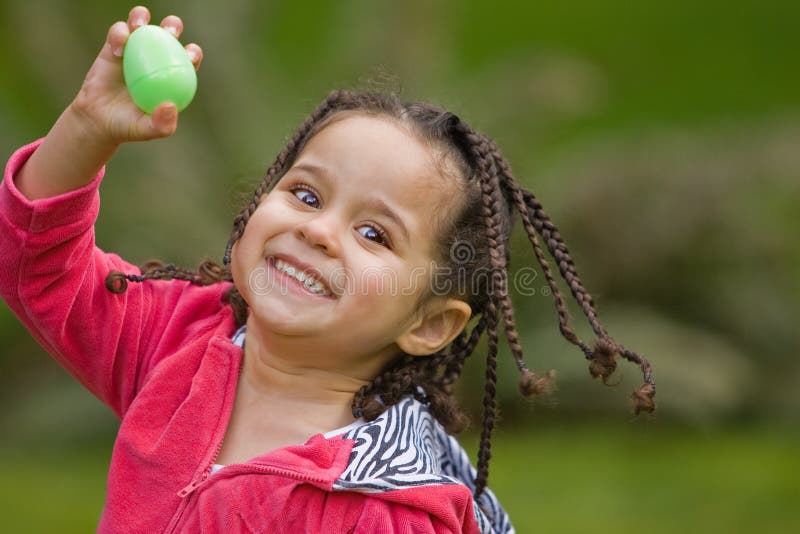 Young happy girl holding up a green plastic Easter egg. Young happy girl holding up a green plastic Easter egg